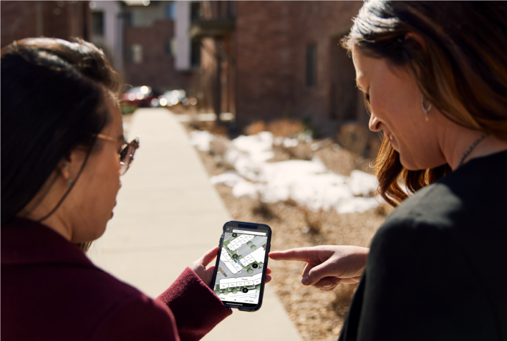 Two people walking outdoors holding phone with Sight Map interface showing geo referencing location feature.